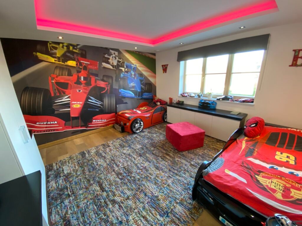 Children’s bedroom designed and fitted by Torwood in Purley, featuring modern recessed ceiling lighting, full wall racing wallpaper, and custom storage units