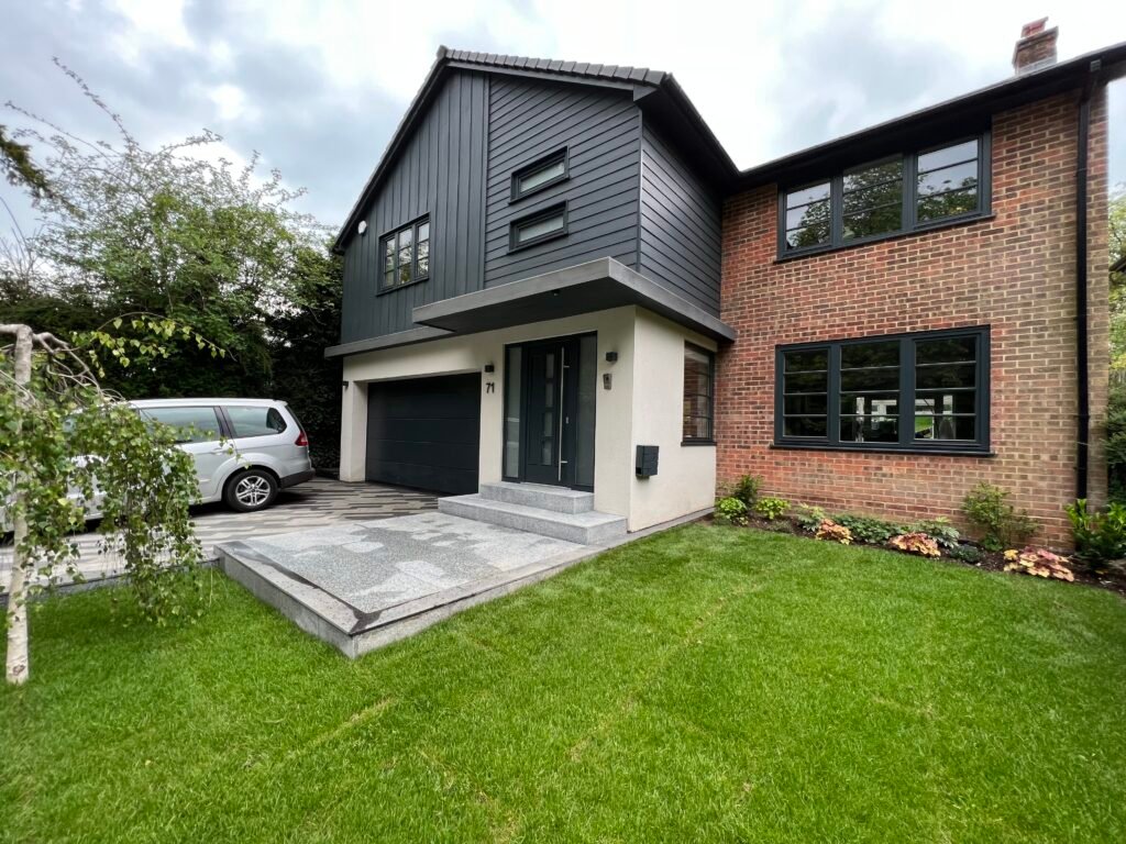Front elevation of a renovated house in Caterham featuring timber windows, a new garage door, and anthracite cladding by Torwood Interiors