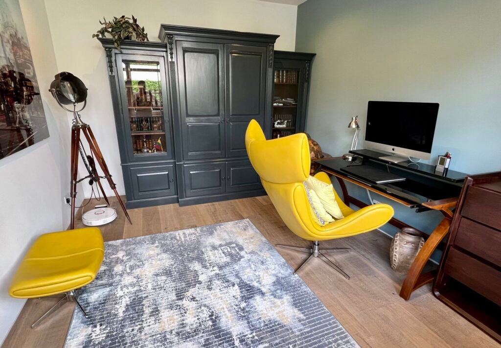Stylish home office in Purley with yellow chair, oak flooring, and bespoke cabinetry by Torwood Interiors
