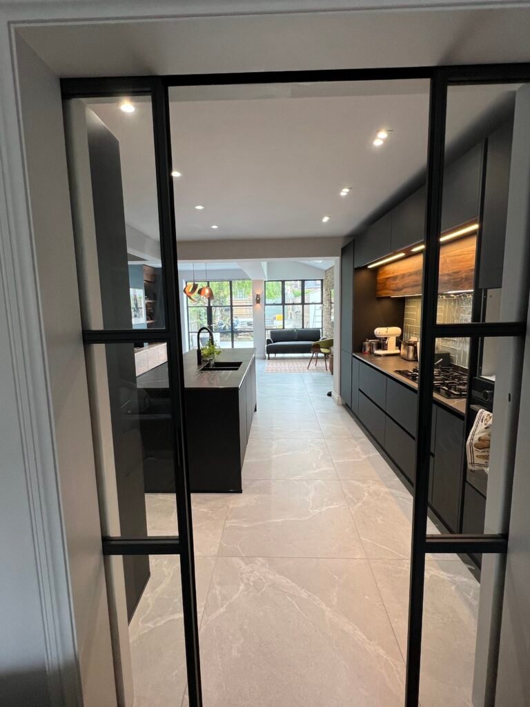 Open-plan kitchen in St Margarets viewed through slim-profile internal glass doors — designed and built by Torwood
