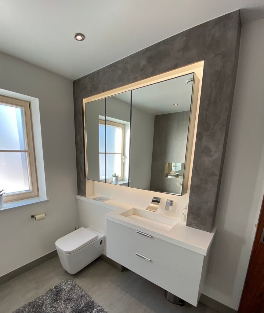 Modern bathroom with illuminated mirror, integrated vanity, and minimalist finishes — designed and built by Torwood Interiors in Purley, London