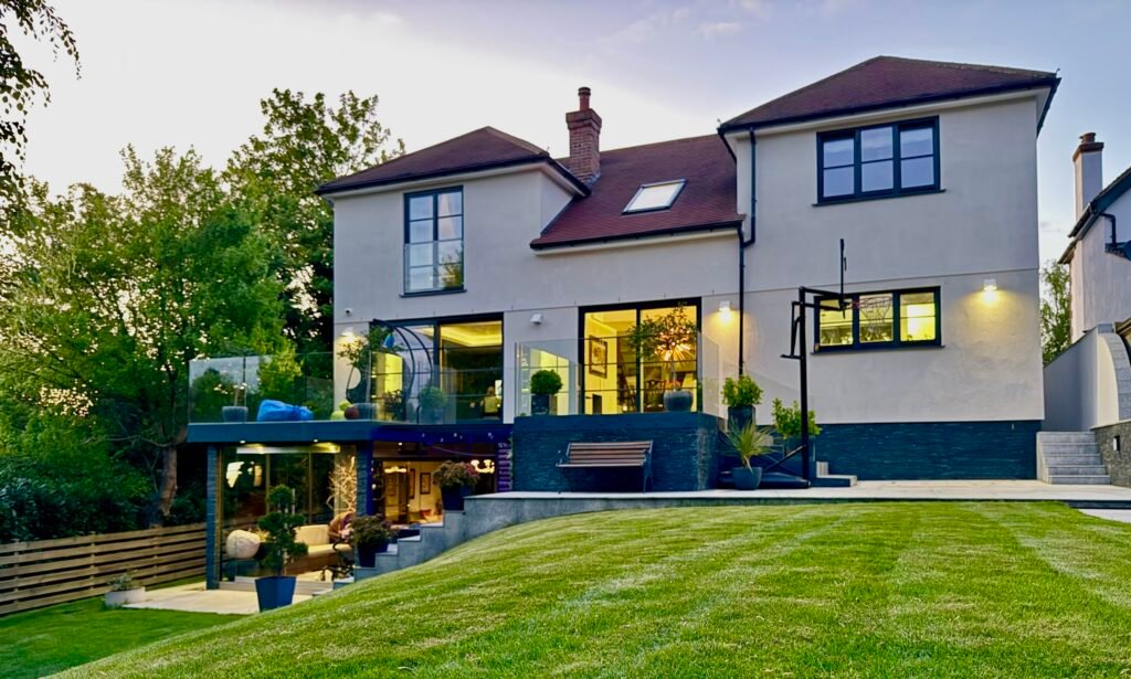 Modern double-storey house extension in Purley with glass balustrade terrace and landscaped garden, built by Torwood