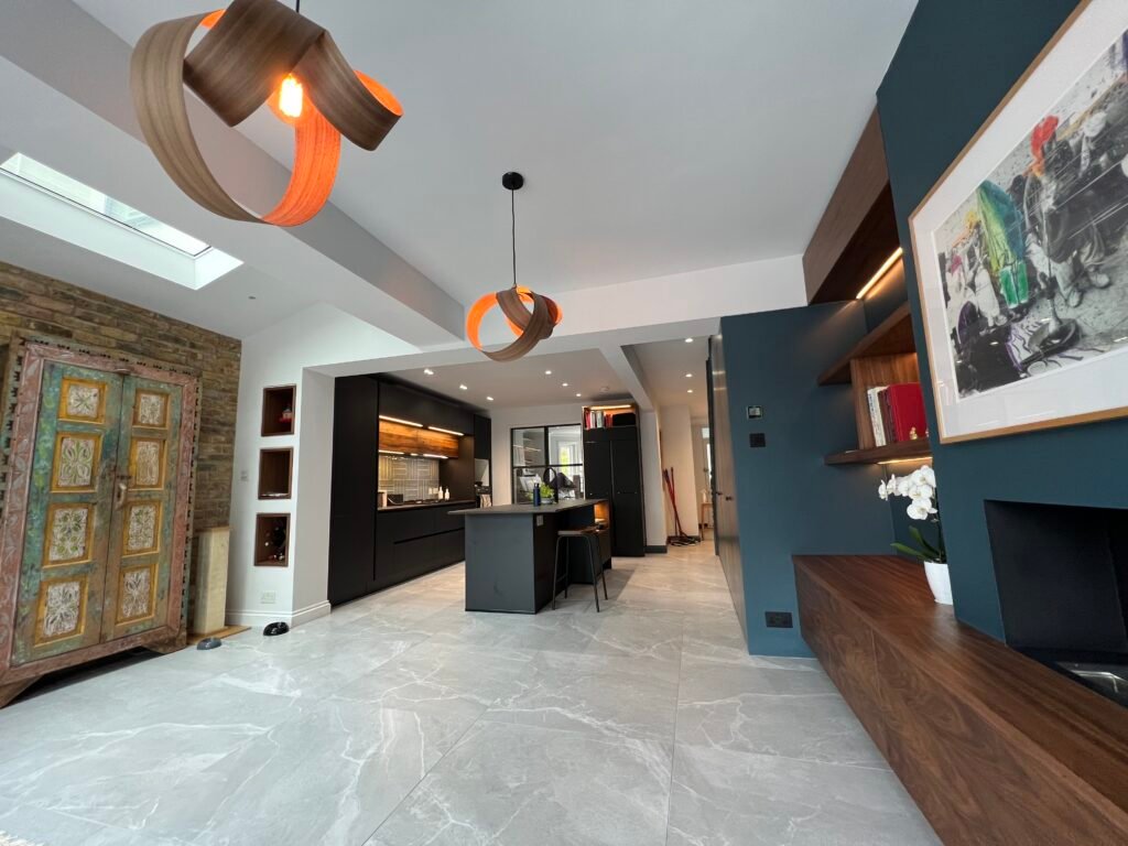 Open-plan kitchen and dining extension in St Margarets featuring bespoke walnut joinery, dark cabinetry, and contemporary pendant lighting — designed and built by Torwood Interiors