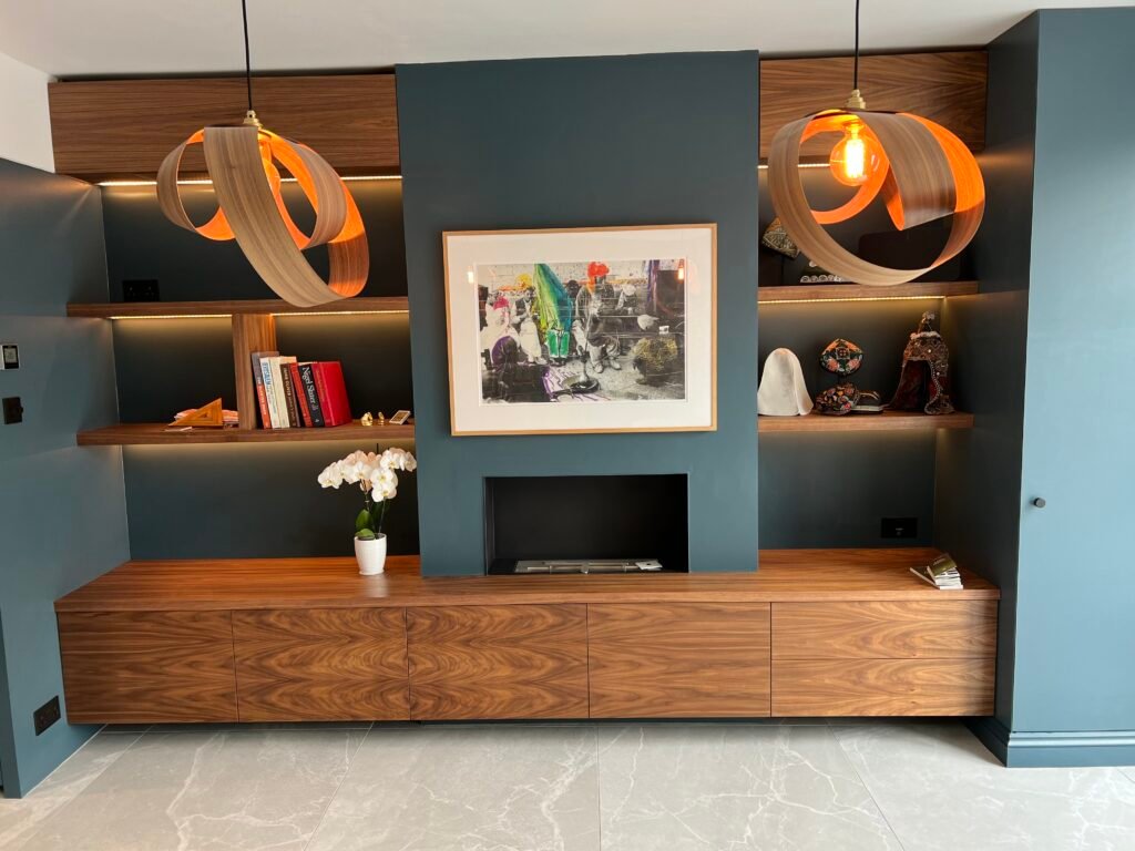 Bespoke walnut joinery unit with integrated fireplace and LED-lit shelving, designed and built by Torwood Interiors in Richmond.
