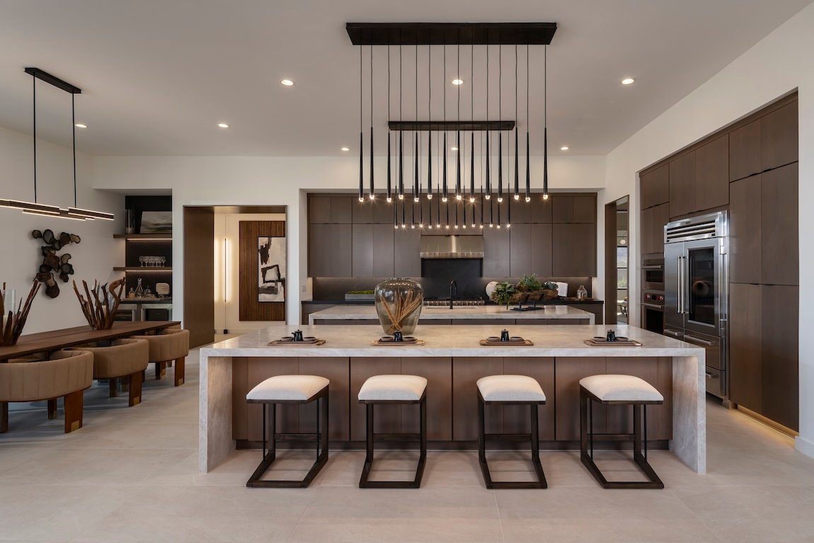 Open-plan kitchen with large island, pendant lighting and dark cabinetry