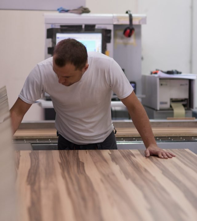 worker in a factory of wooden furniture Young worker works in a factory for the production of wooden furniture